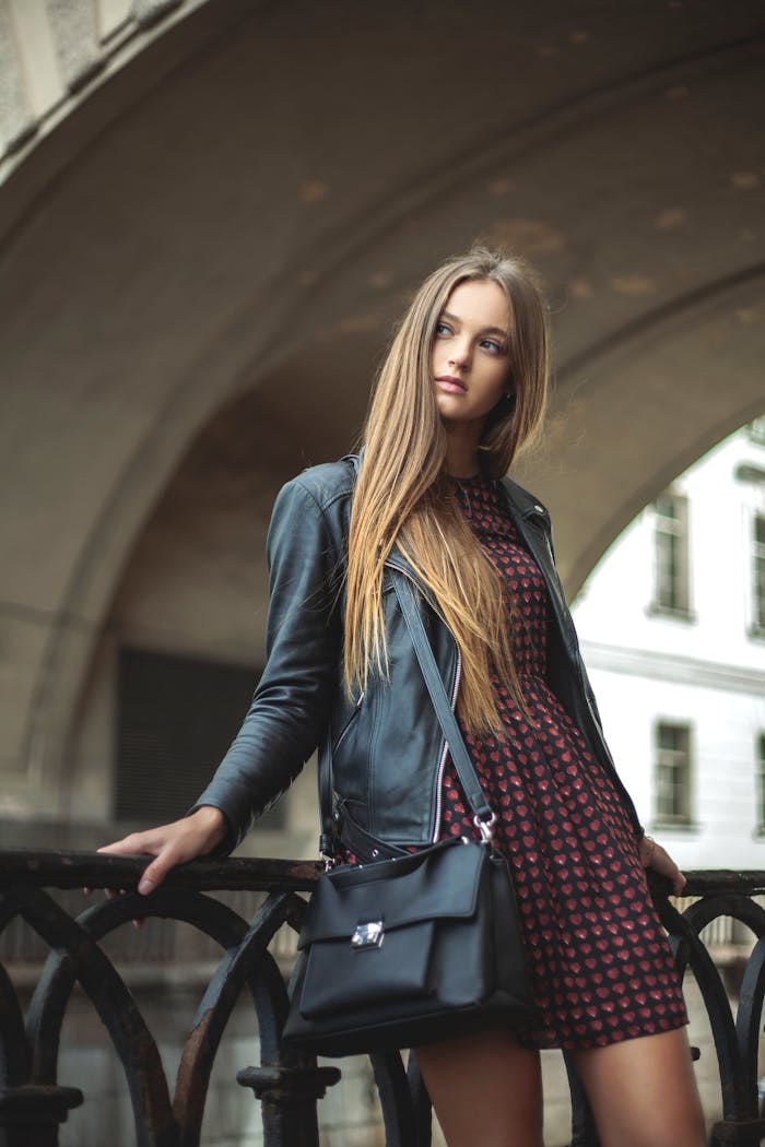 Woman Wearing Black Full-zip Leather Jacket Leaning on Black Metal Fence